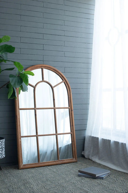 Large arched mirror with brown fir wood frame and window-pane design, leaning on gray brick wall on Tampa Home & Garden Store