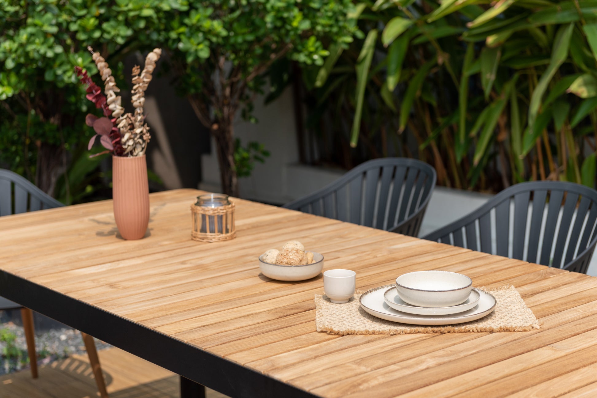 Portals dark rectangular teak outdoor table with 8 Nassau black dining chairs on a wooden patio on Tampa Home & Garden Store