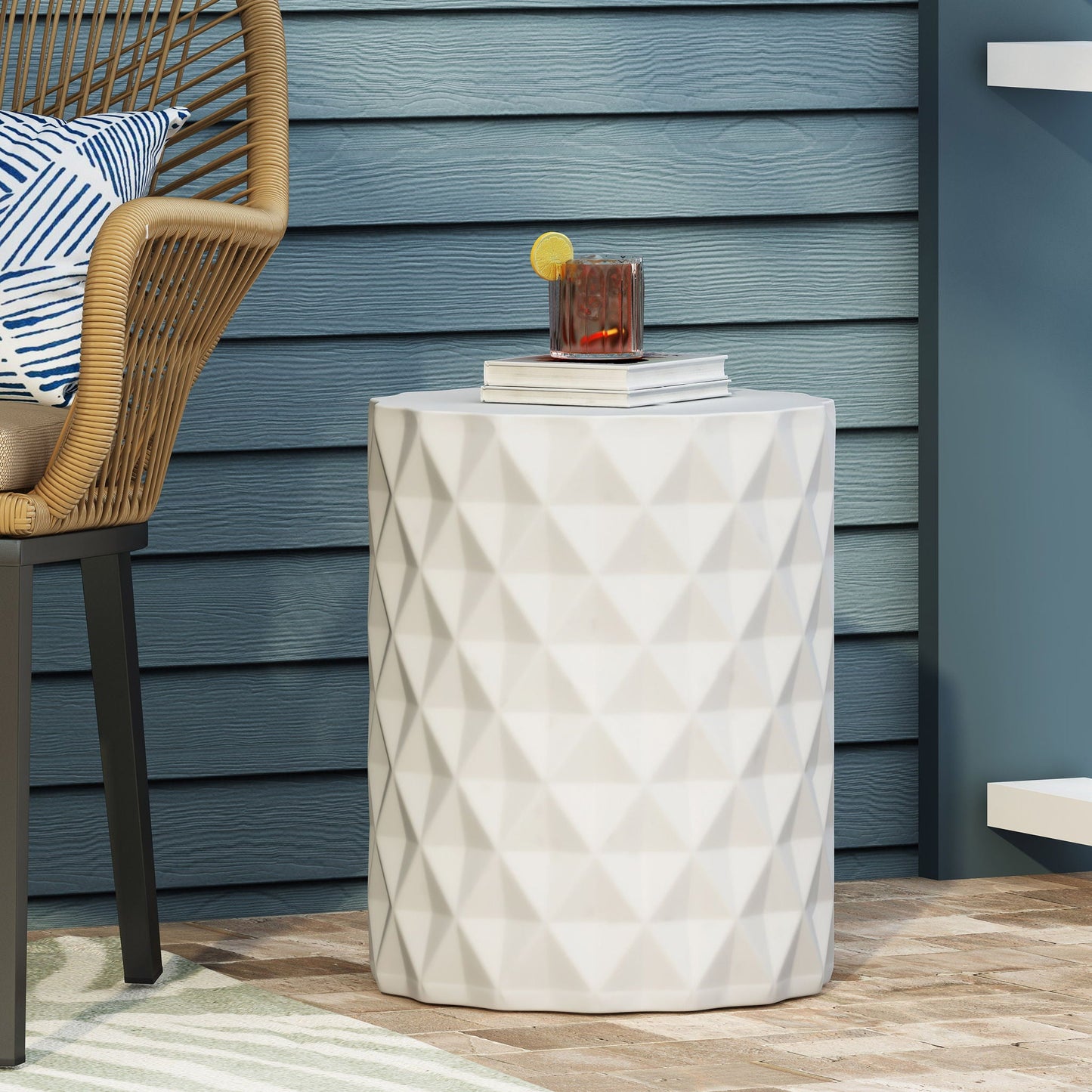 Outdoor lightweight concrete side table antique white with faceted surface beside wicker chair on Tampa Home & Garden Store