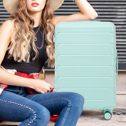 Mint green hard-shell spinner luggage with four wheels beside a seated woman on Tampa Home & Garden Store