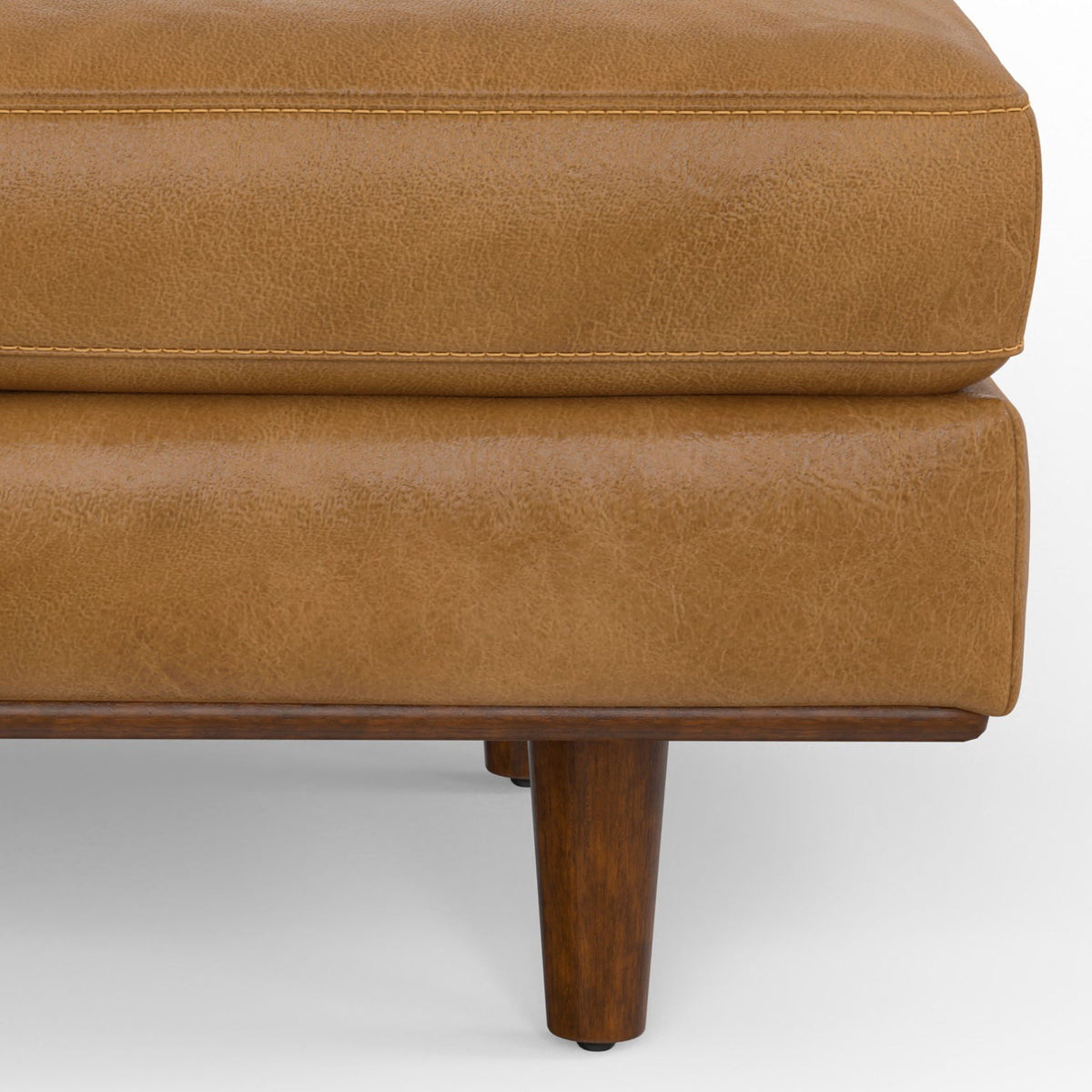 Morrison handcrafted ottoman in tan leather with exposed stitched seam and wooden leg on Tampa Home & Garden Store