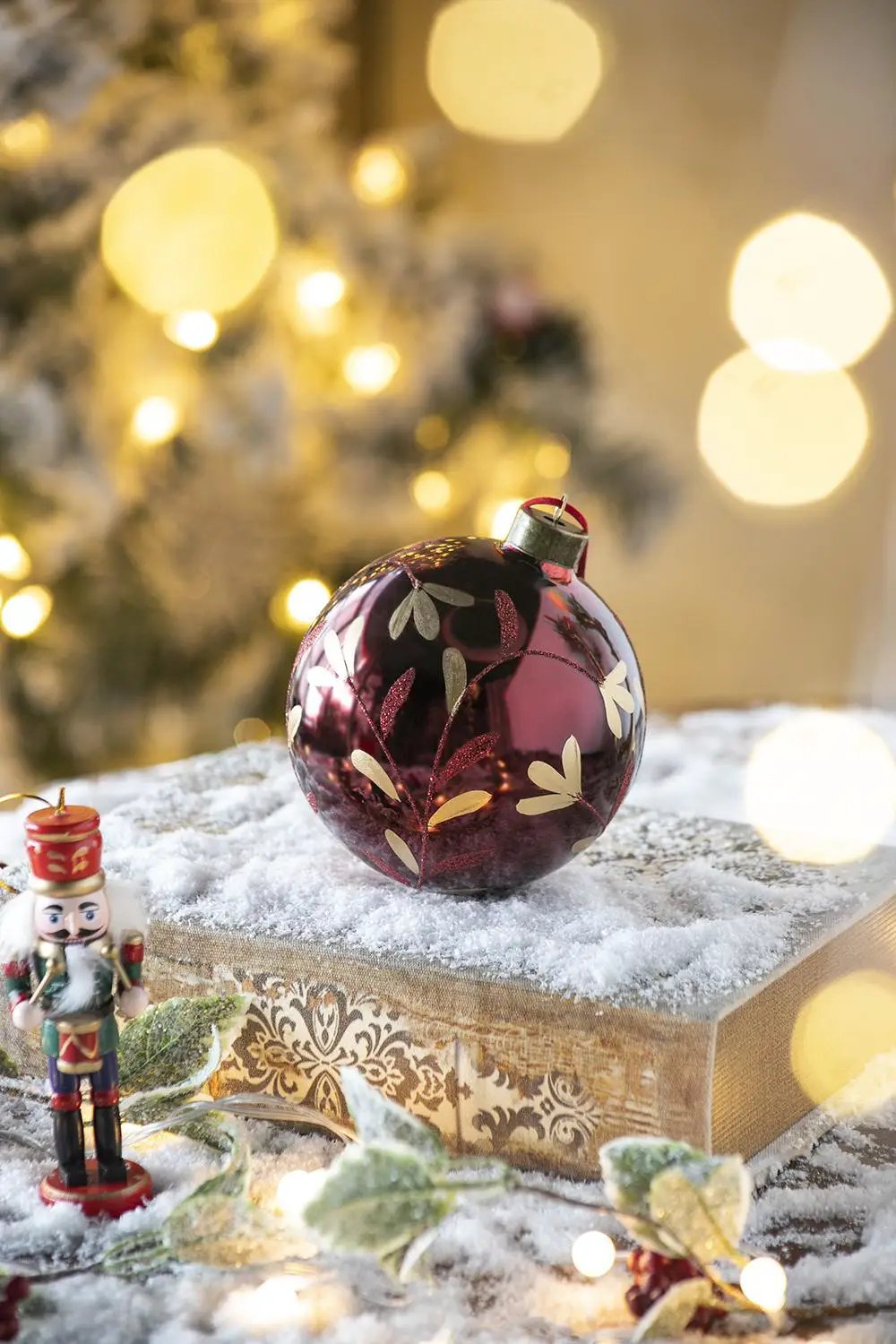 burgundy glass Christmas ball ornament with gold leaf botanical design on a snow-dusted book on Tampa Home & Garden Store