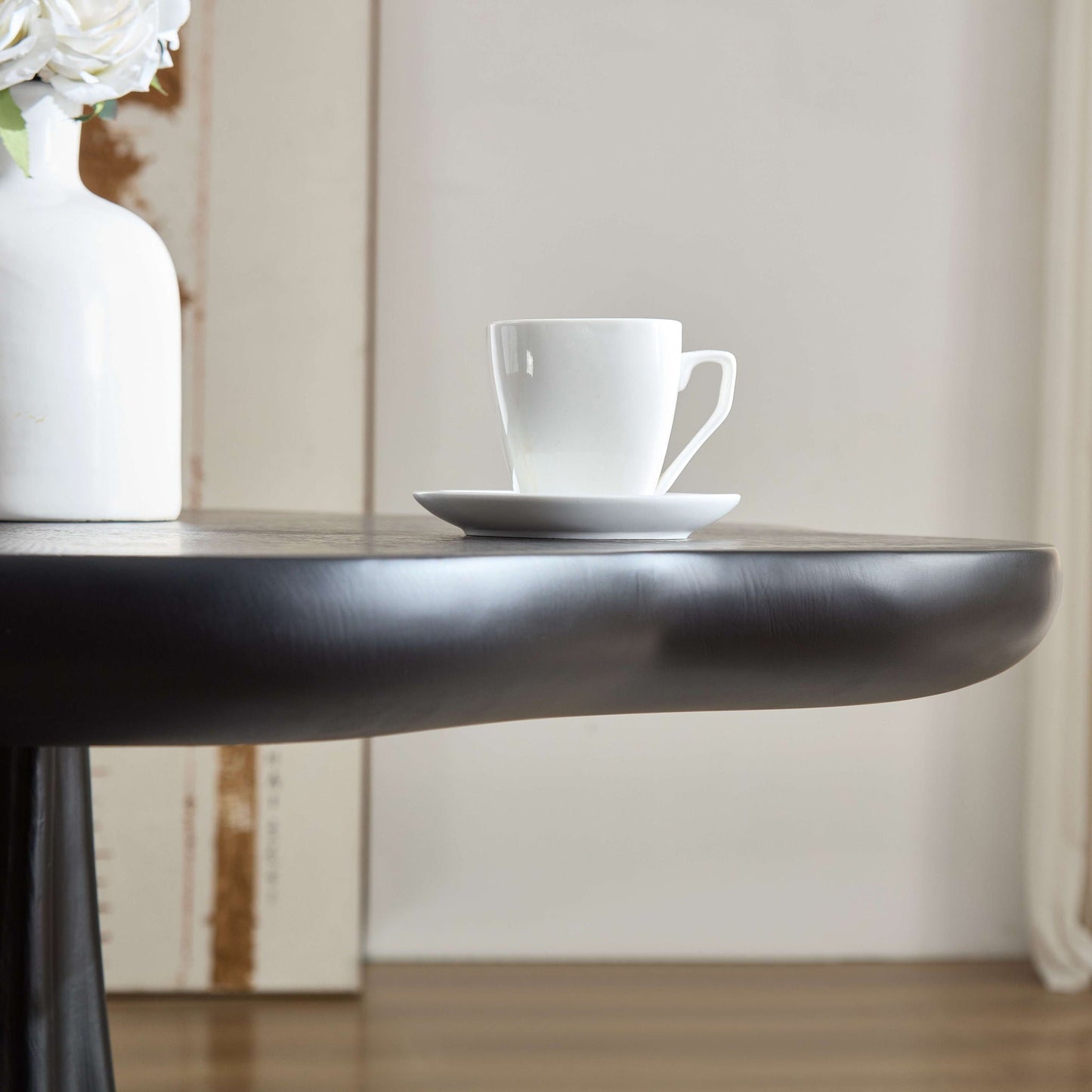 Sculptural round black dining table with petal shape root texture, shown with white cup on Tampa Home & Garden Store