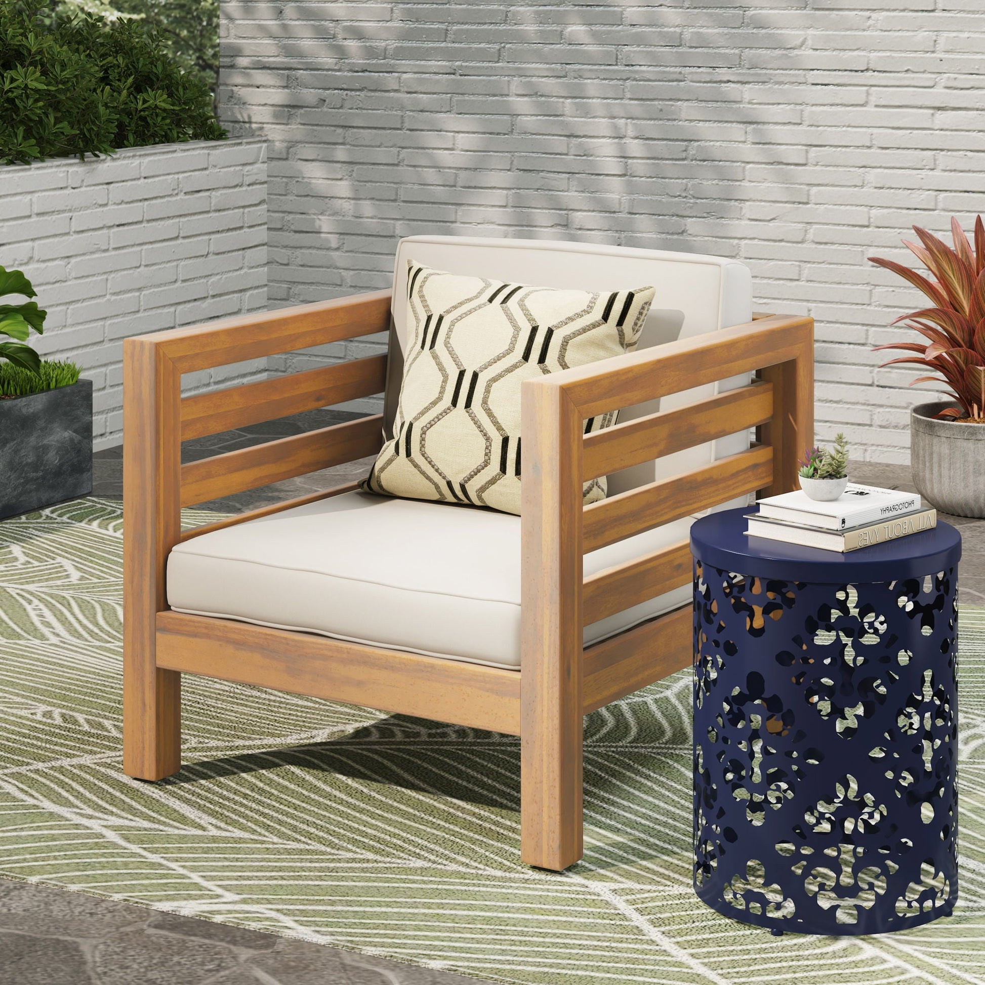 Outdoor Acacia wood patio armchair with white fabric cushion and patterned throw pillow on Tampa Home & Garden Store