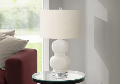 Contemporary cream ceramic table lamp with stacked sphere base and linen shade atop glass table on Tampa Home & Garden Store
