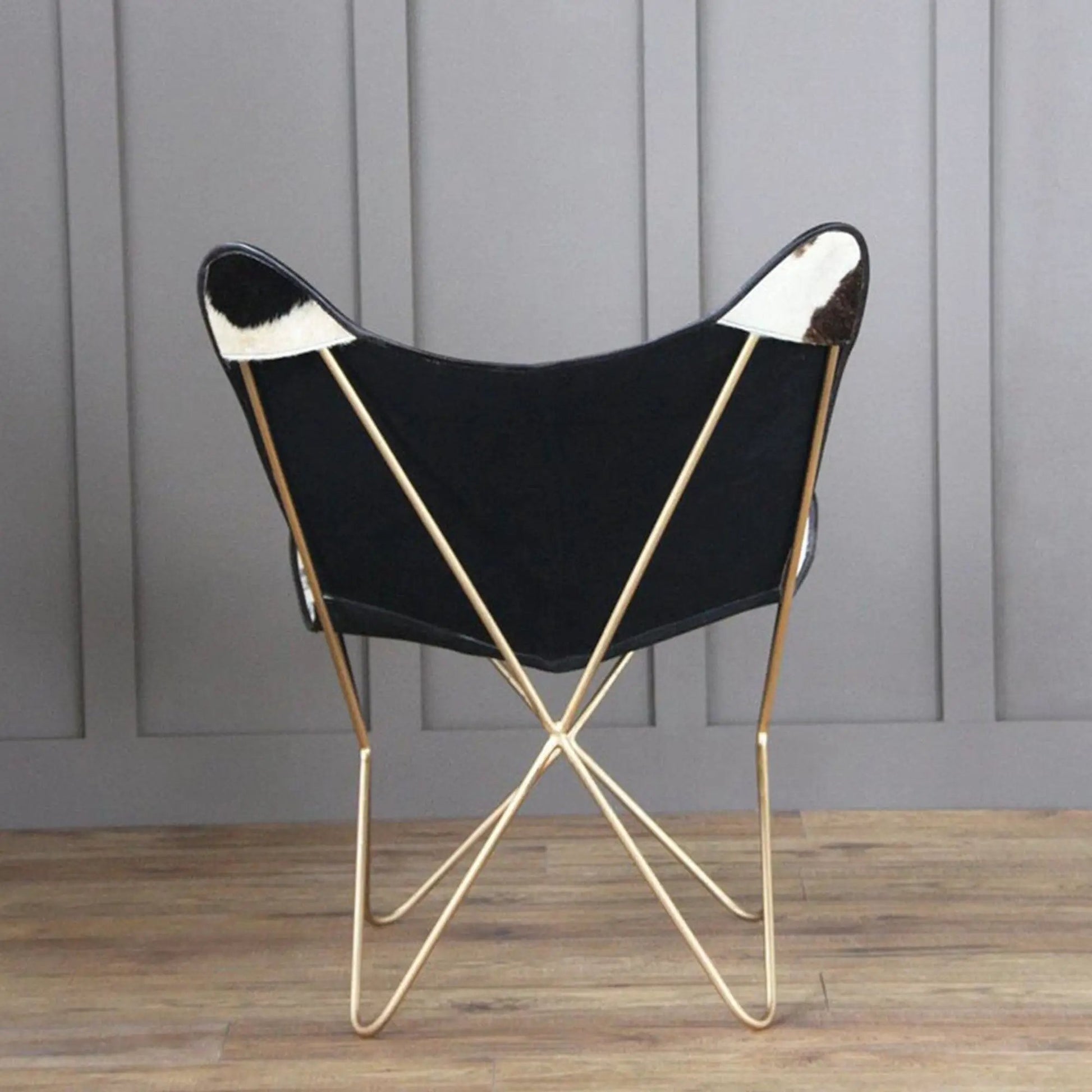 The Holsteins Butterfly Chair with black seat and cowhide patches, slender gold legs on Tampa Home & Garden Store