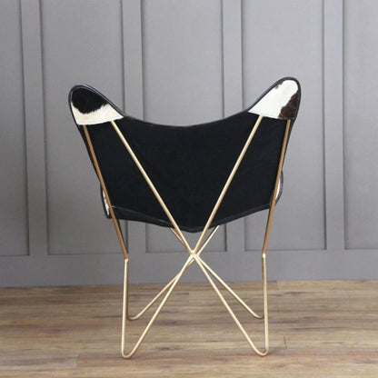 The Holsteins Butterfly Chair with black seat and cowhide patches, slender gold legs on Tampa Home & Garden Store