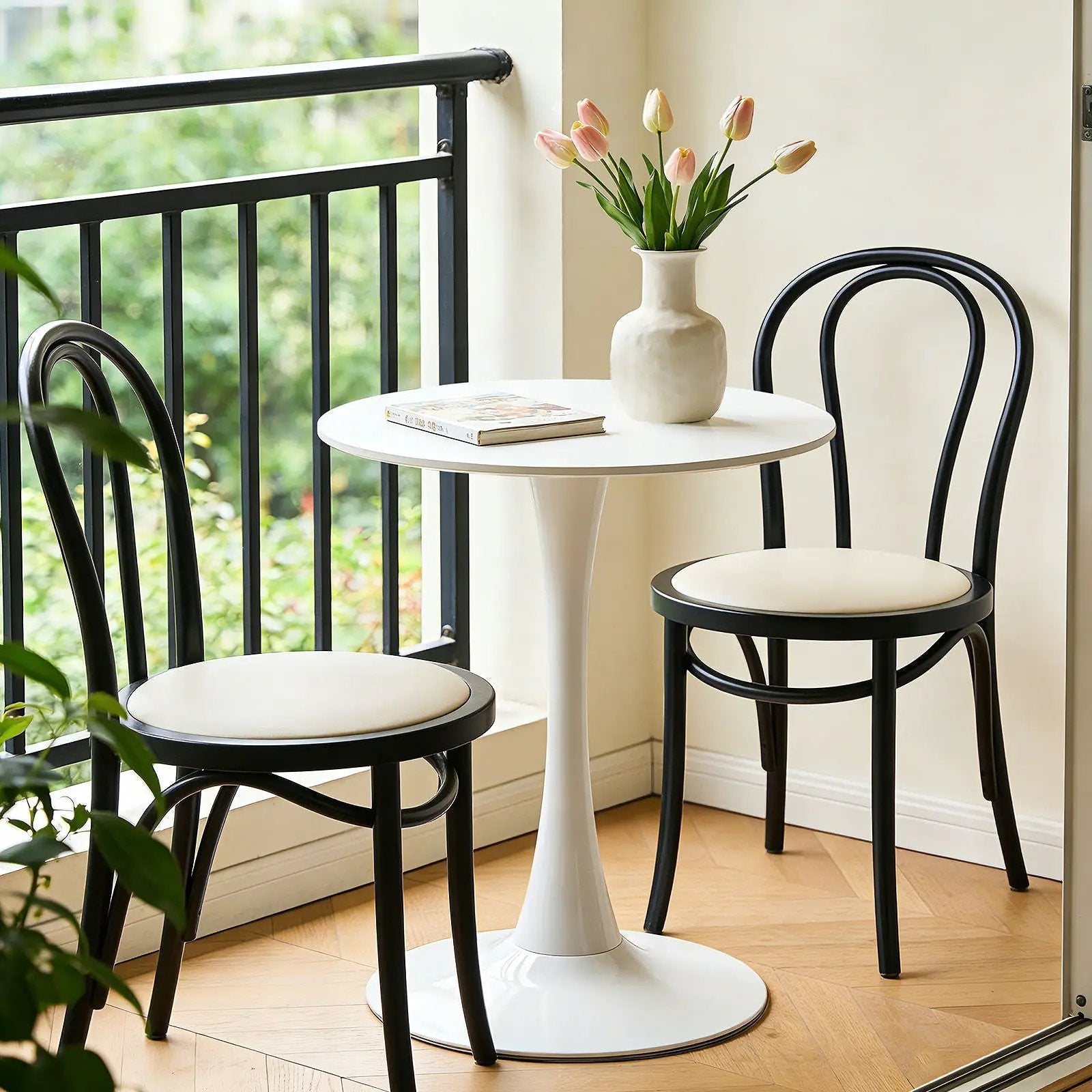 Round dining table with tulip-style white pedestal base, black chairs and pink tulips on top on Tampa Home & Garden Store