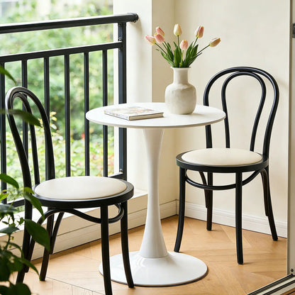 Round dining table with tulip-style white pedestal base, black chairs and pink tulips on top on Tampa Home & Garden Store