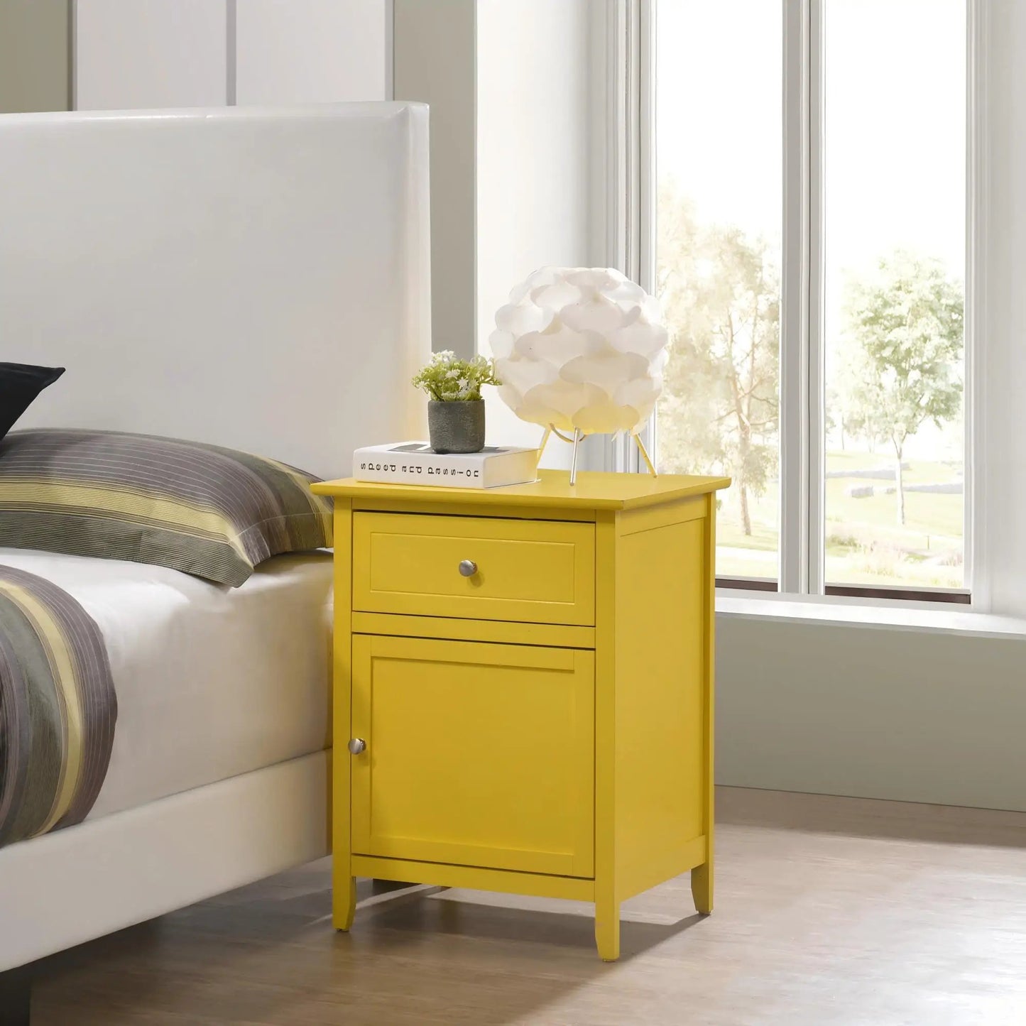 Yellow 1-drawer 1-door accent nightstand with a silver knob beside the bed; topped with books and a plant on Tampa Home & Garden Store