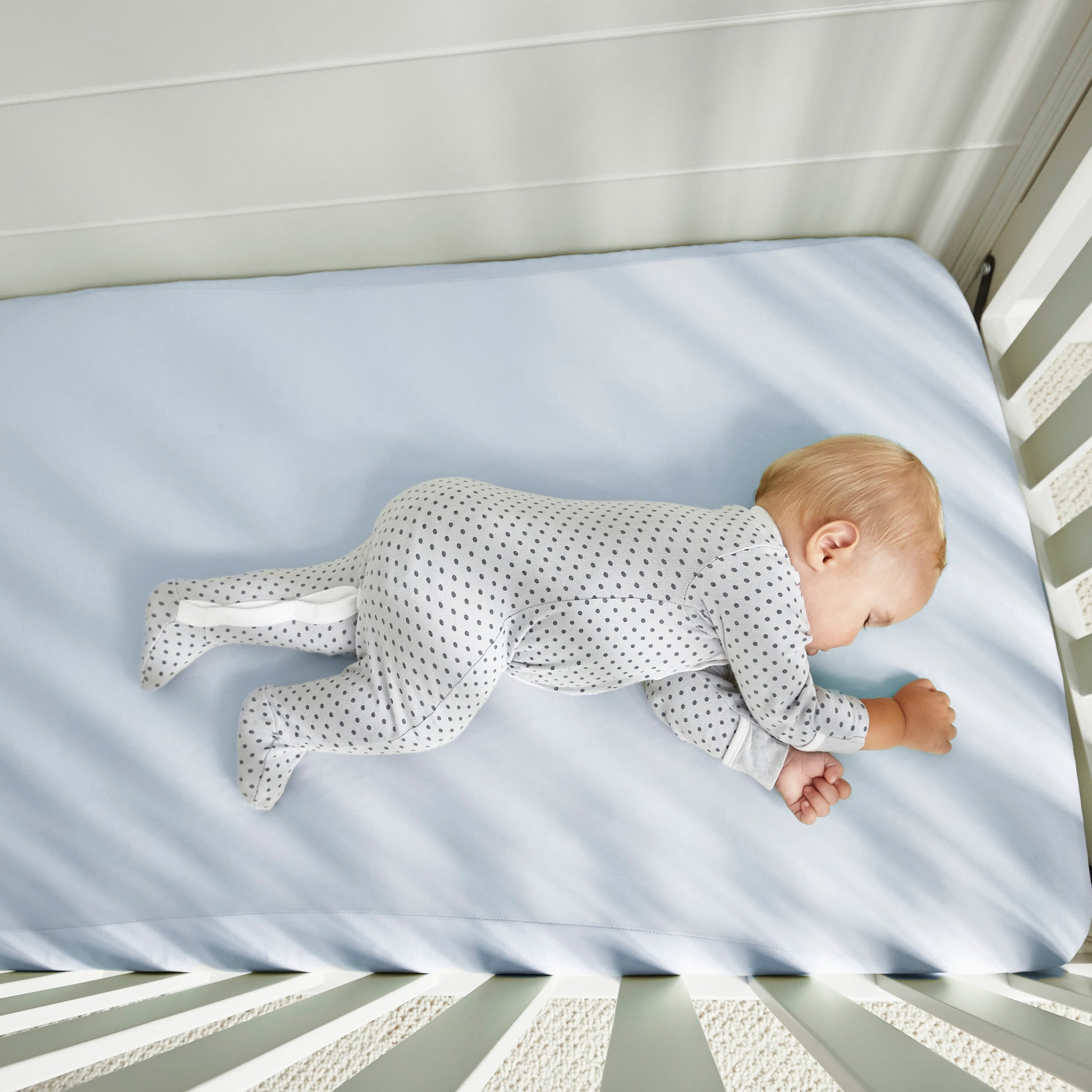 BedGear Dri-Tec baby blue crib sheet on crib mattress with sleeping baby in dotted sleeper on Tampa Home & Garden Store