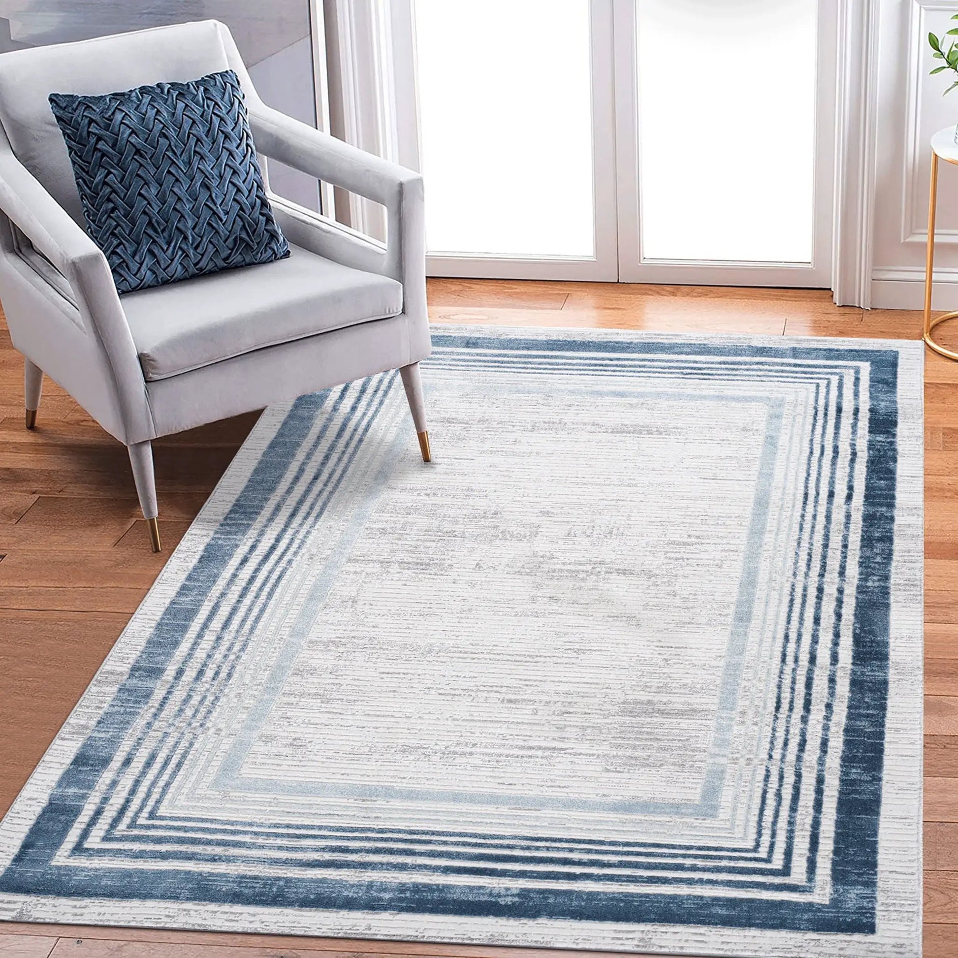 Marfi bordered area rug by Unique Piece Furniture in blue-gray on a light hardwood floor on Tampa Home & Garden Store