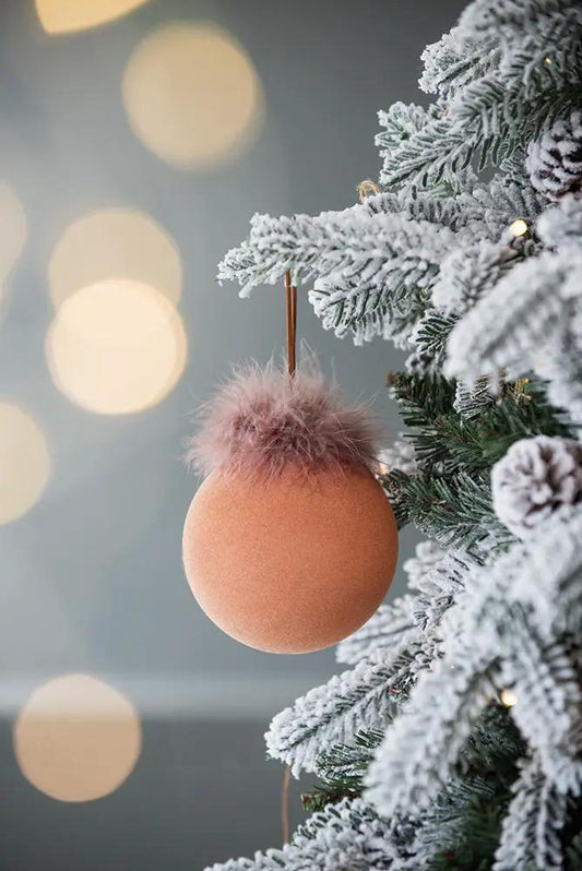 Peach glass Christmas ball ornament with fluffy pink fur topper on frosted pine branch on Tampa Home & Garden Store