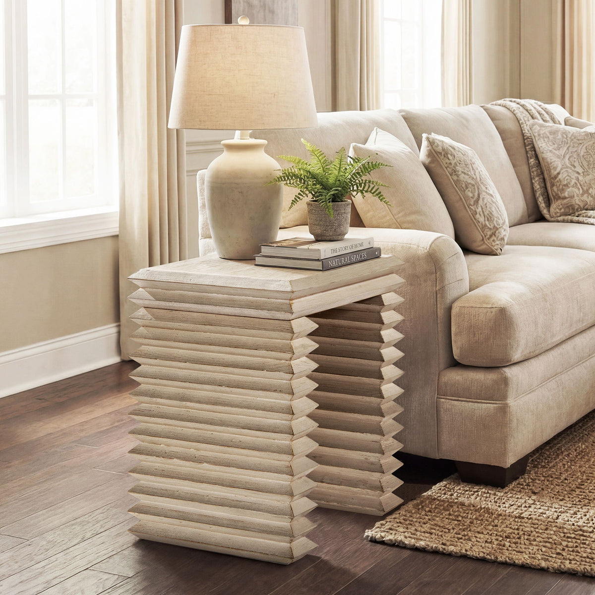 Geometric waterfall console table in light wood with stacked base beside a beige sofa on Tampa Home & Garden Store