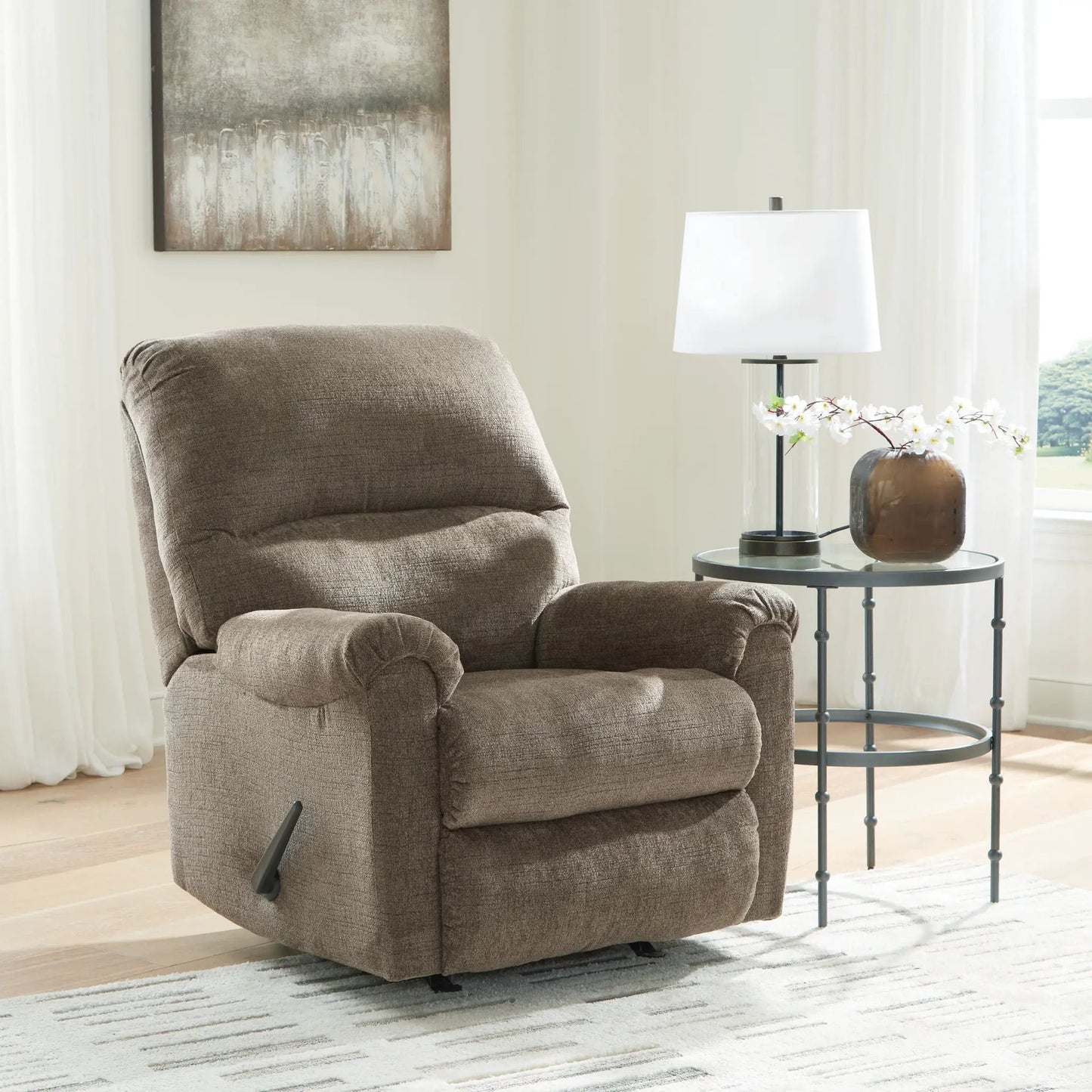 Stonemeade rocker recliner in brown fabric beside a round glass-top side table with a white lamp on Tampa Home & Garden Store