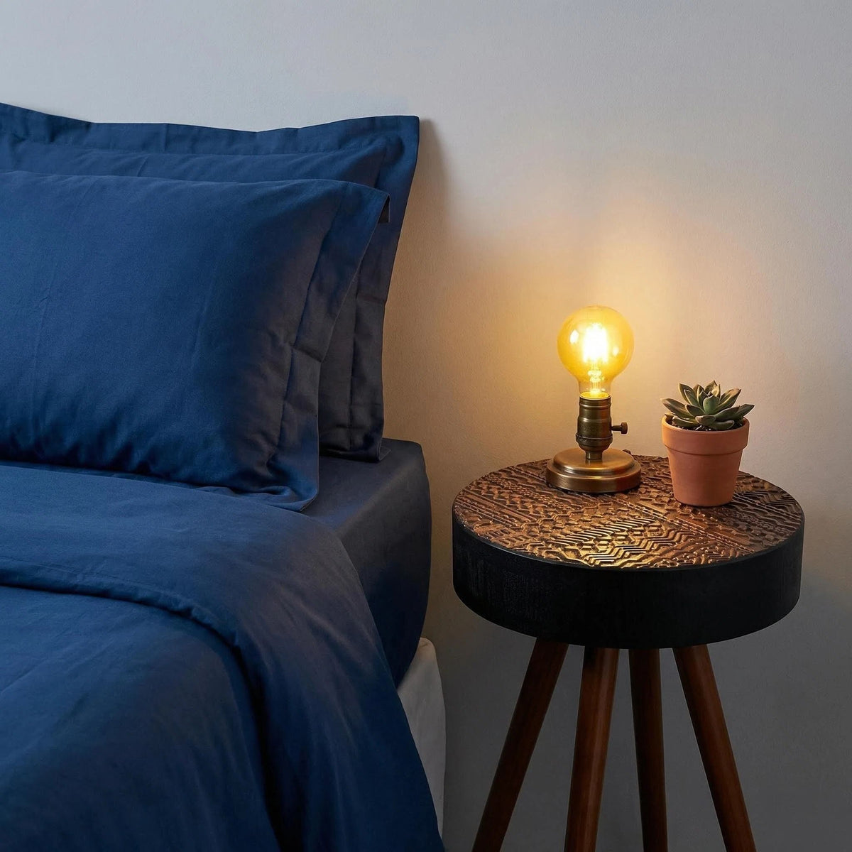 Round carved-top coffee table with dark brown wood legs beside blue bedding HouseOfZazla on Tampa Home & Garden Store
