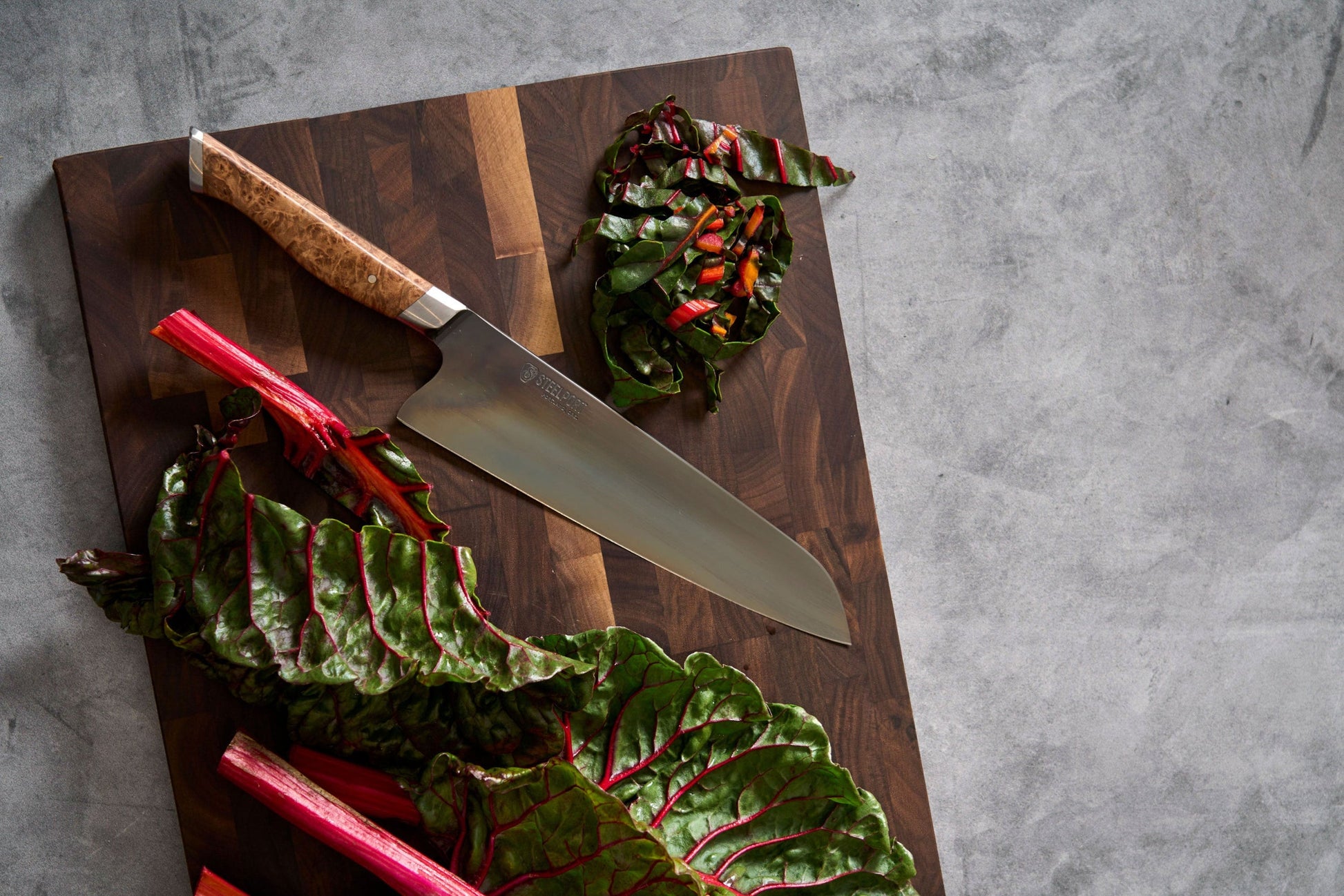 8-inch chef knife STEELPORT Knife Co. on dark wood cutting board with rainbow chard red stems on Tampa Home & Garden Store