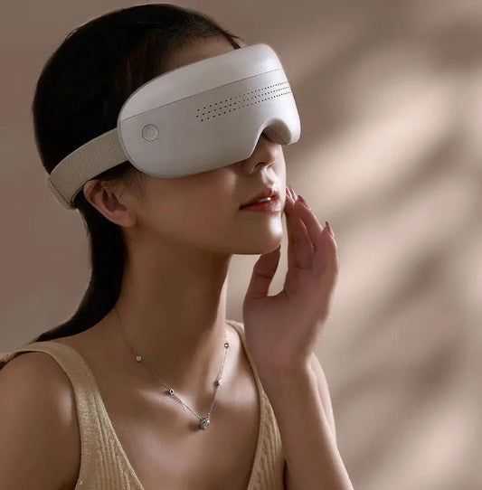 Warm eye massager with 3D vibration and Bluetooth; white massager with beige strap over eyes on Tampa Home & Garden Store
