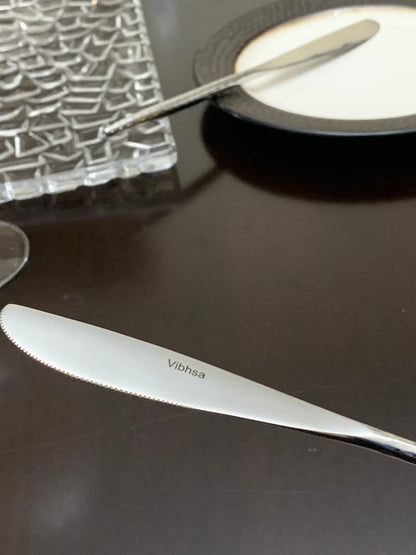 Vibhsa 36-piece flatware knife with white handle and serrated blade on dark table on Tampa Home & Garden Store
