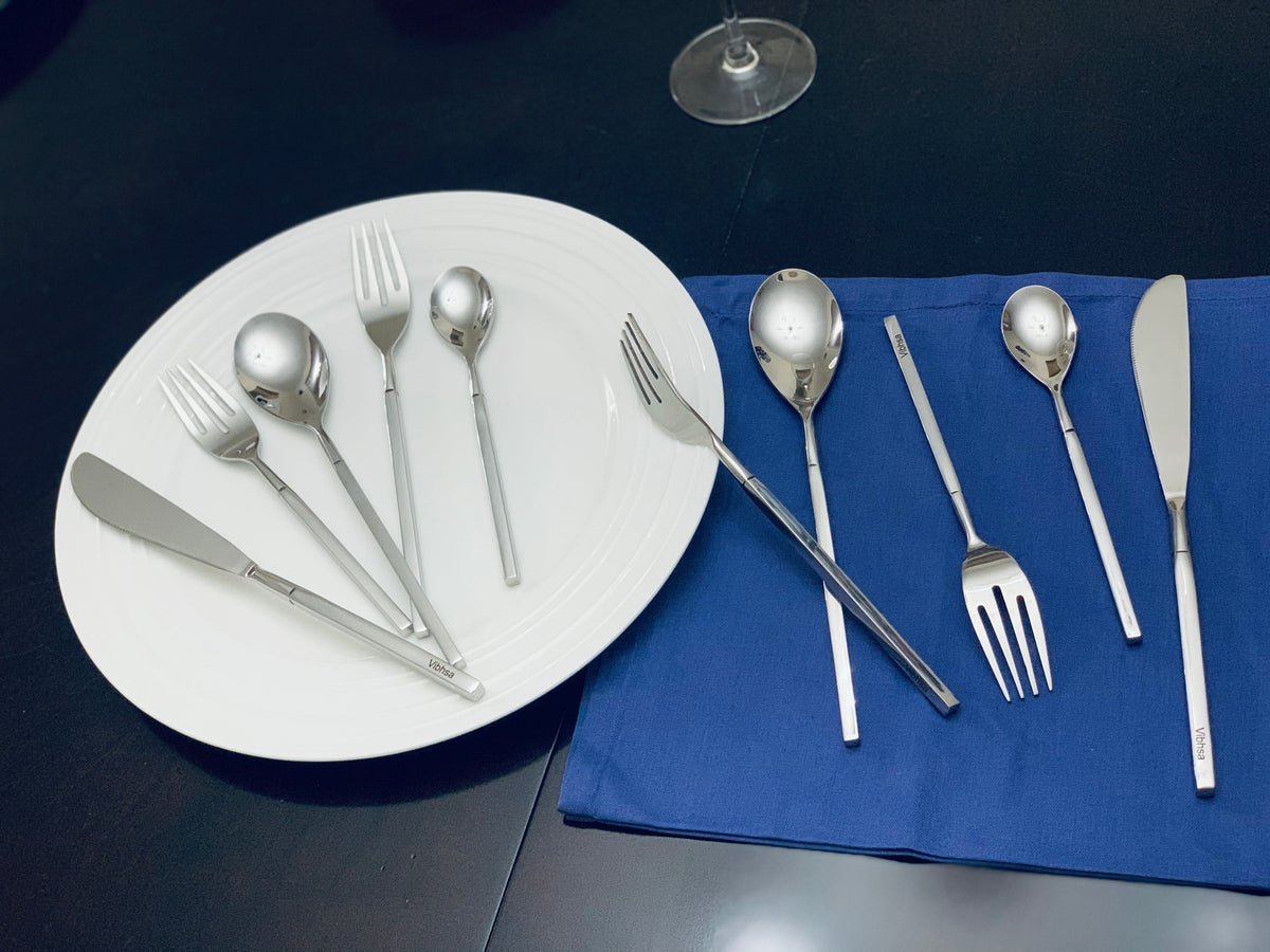 Vibhsa 20-PC Stainless Steel Flatware Set with silver utensils shown on white plate and blue napkin on Tampa Home & Garden Store