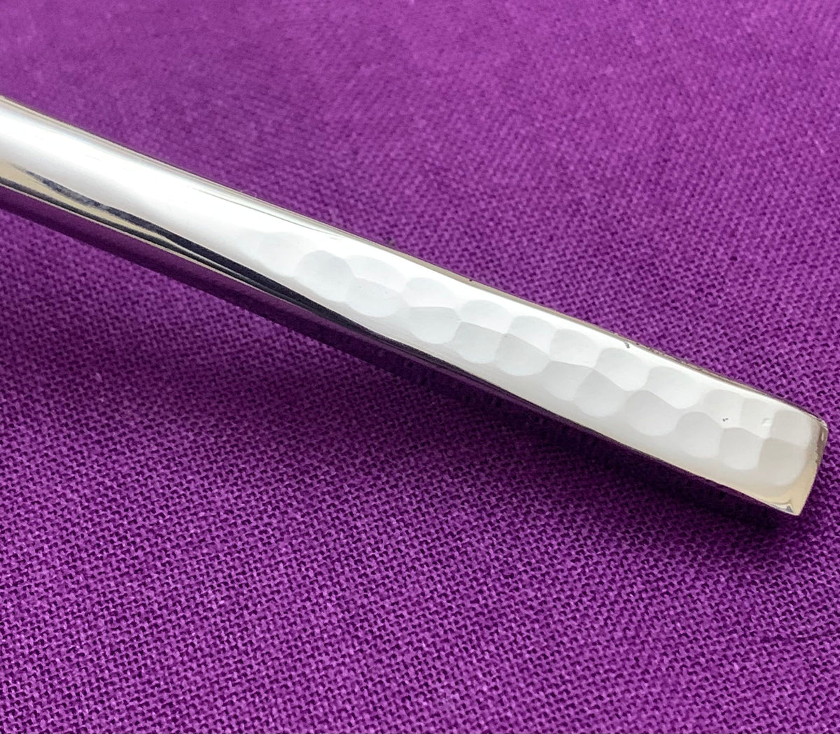 Vibhsa silver flatware handle with hammered texture on purple fabric on Tampa Home & Garden Store