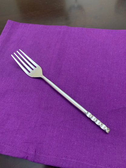 Stainless steel dinner fork on purple fabric on Tampa Home & Garden Store
