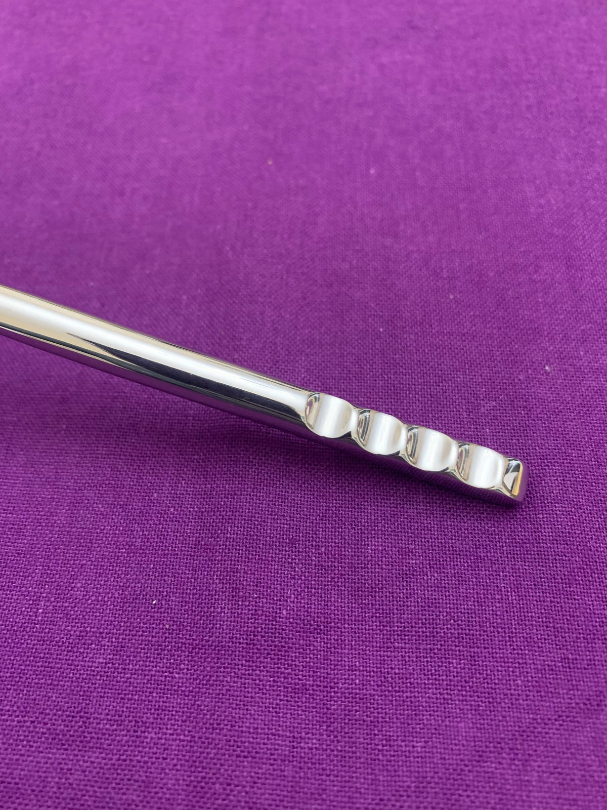 Vibhsa modern stainless steel flatware handle with segmented rounded blocks on purple fabric on Tampa Home & Garden Store