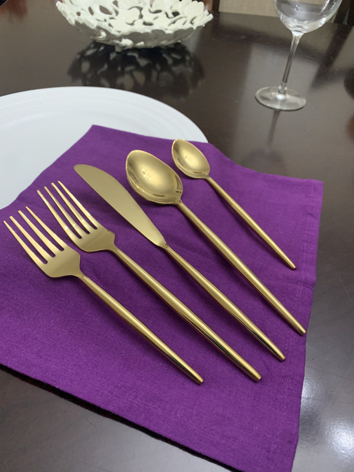 Vibhsa gold flatware set for 4 with forks, knives and spoons on purple napkin on Tampa Home & Garden Store