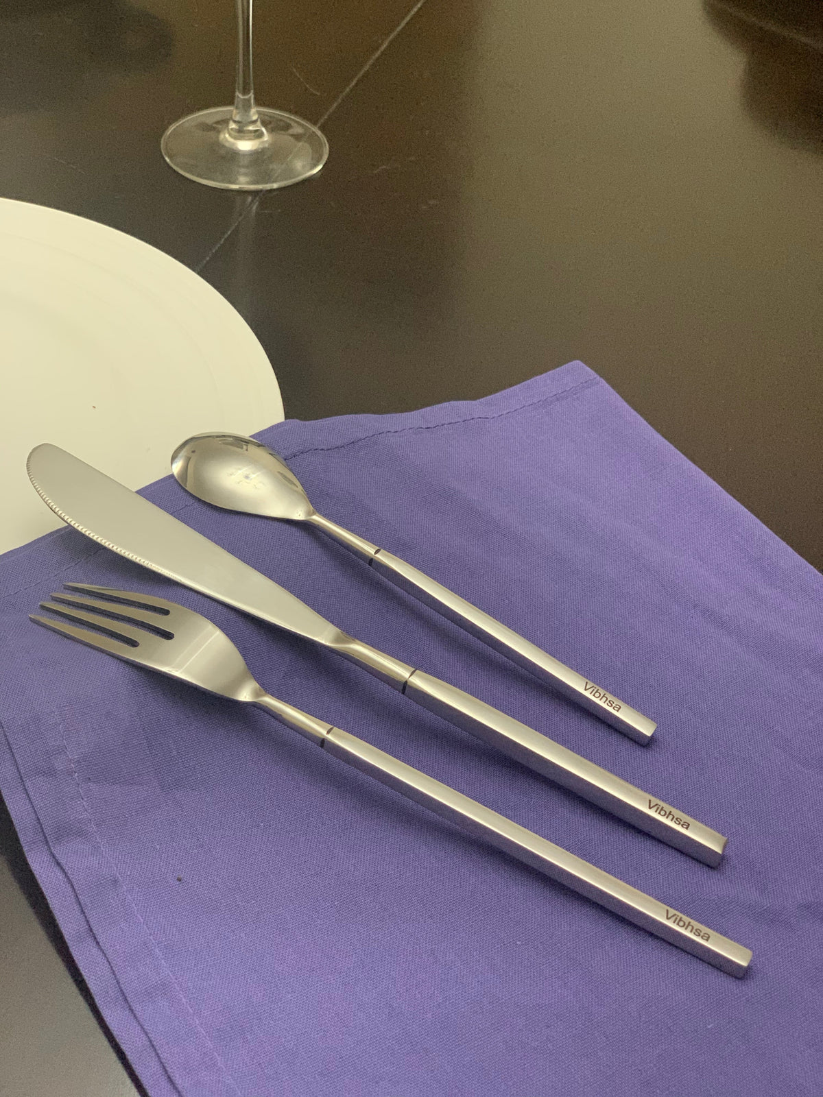 Vibhsa 18-Piece stainless flatware set with knife, fork and dessert spoon on purple napkin on Tampa Home & Garden Store