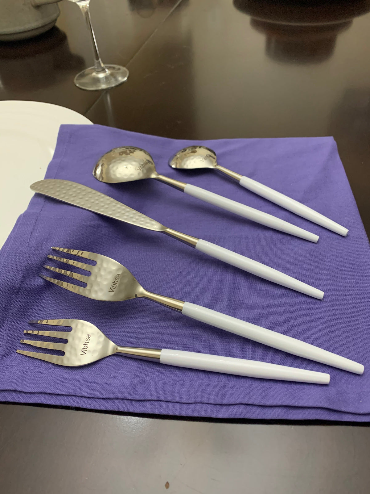 Vibhsa white & silver flatware with hammered spoon bowls and white handles on purple napkin on Tampa Home & Garden Store