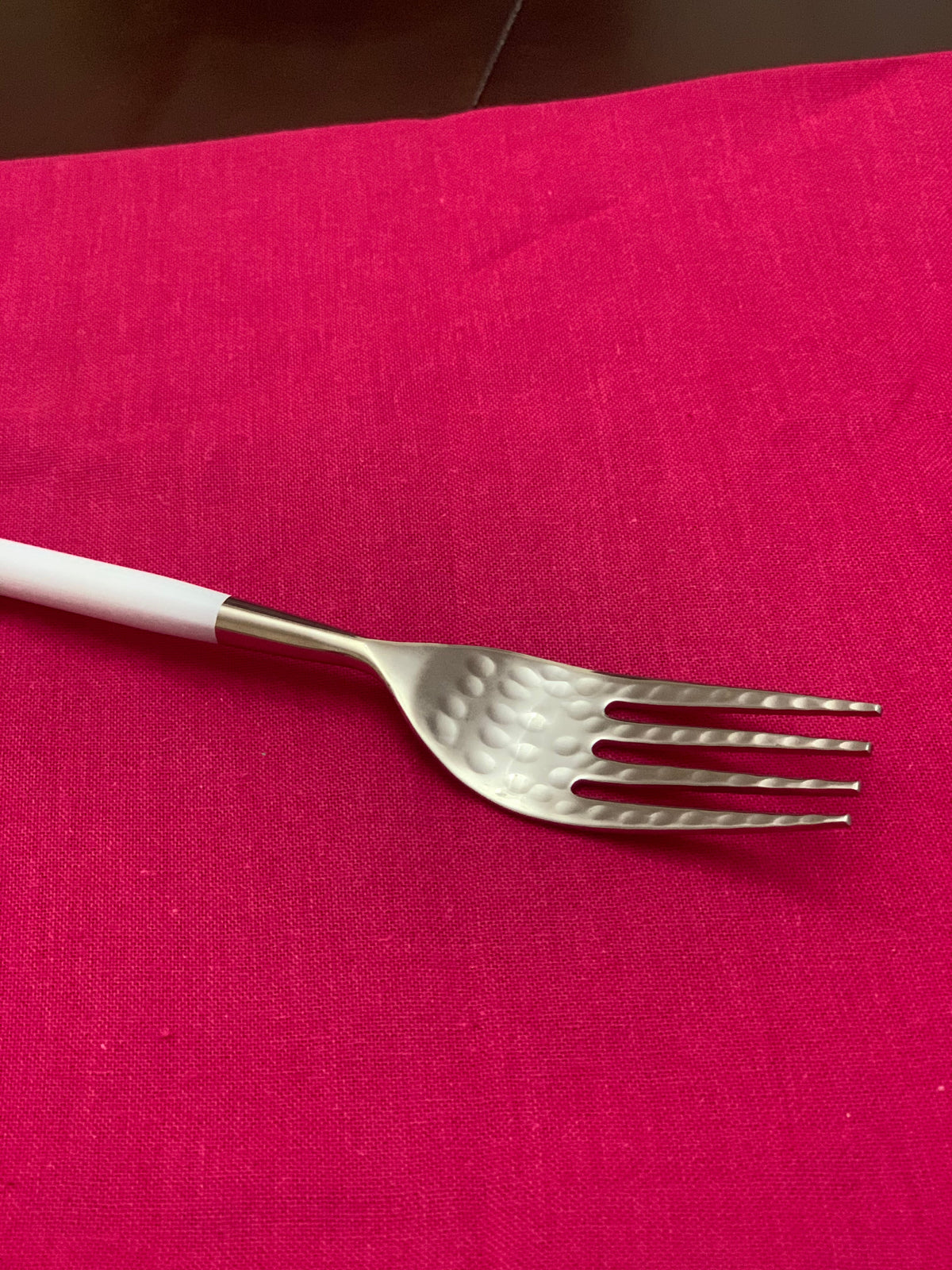 Vibhsa white and silver flatware fork with hammered stainless steel head on pink tablecloth on Tampa Home & Garden Store