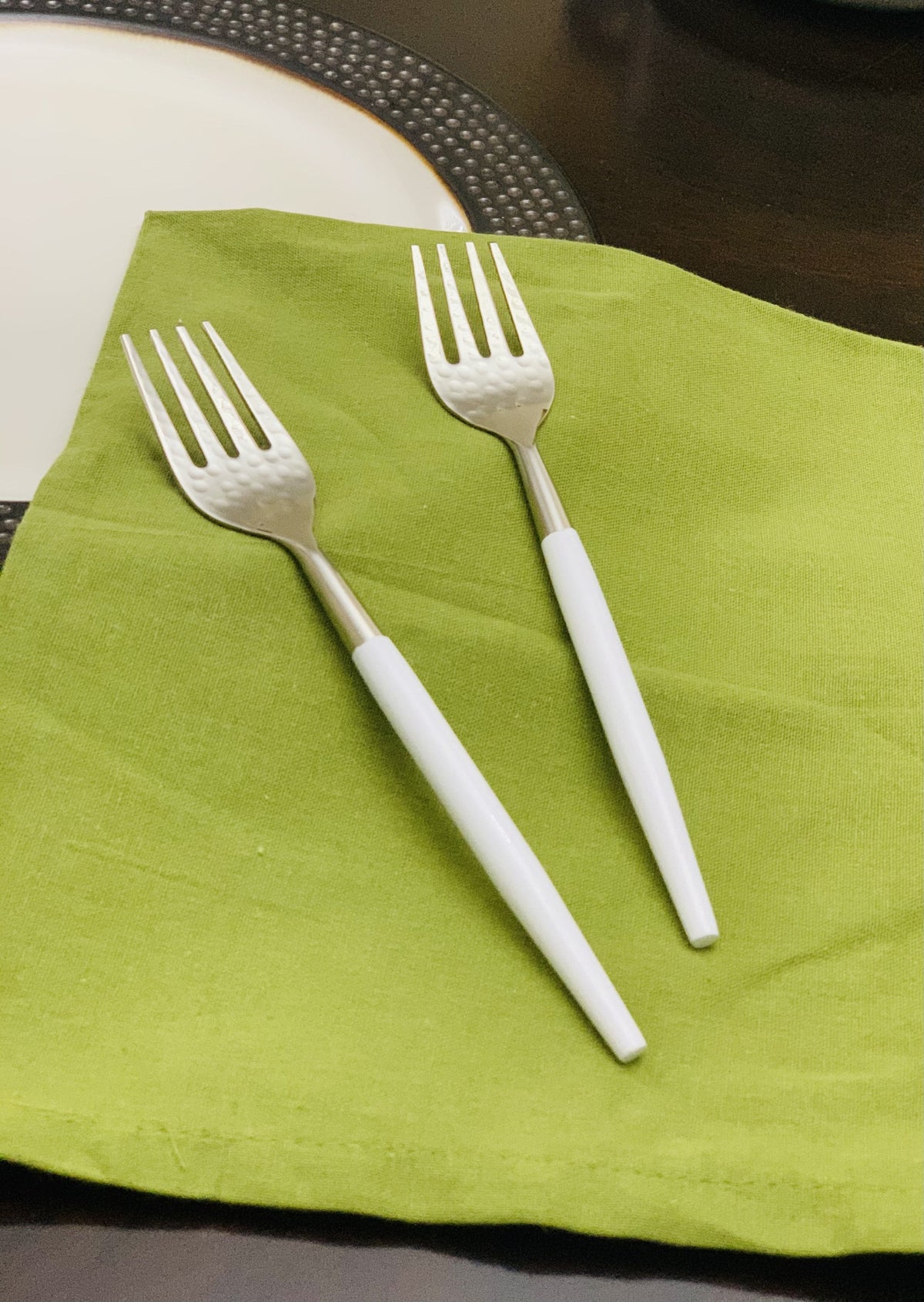 Vibhsa 6-pc stainless steel dinner forks with hammered mouth and white handles on a lime napkin on Tampa Home & Garden Store