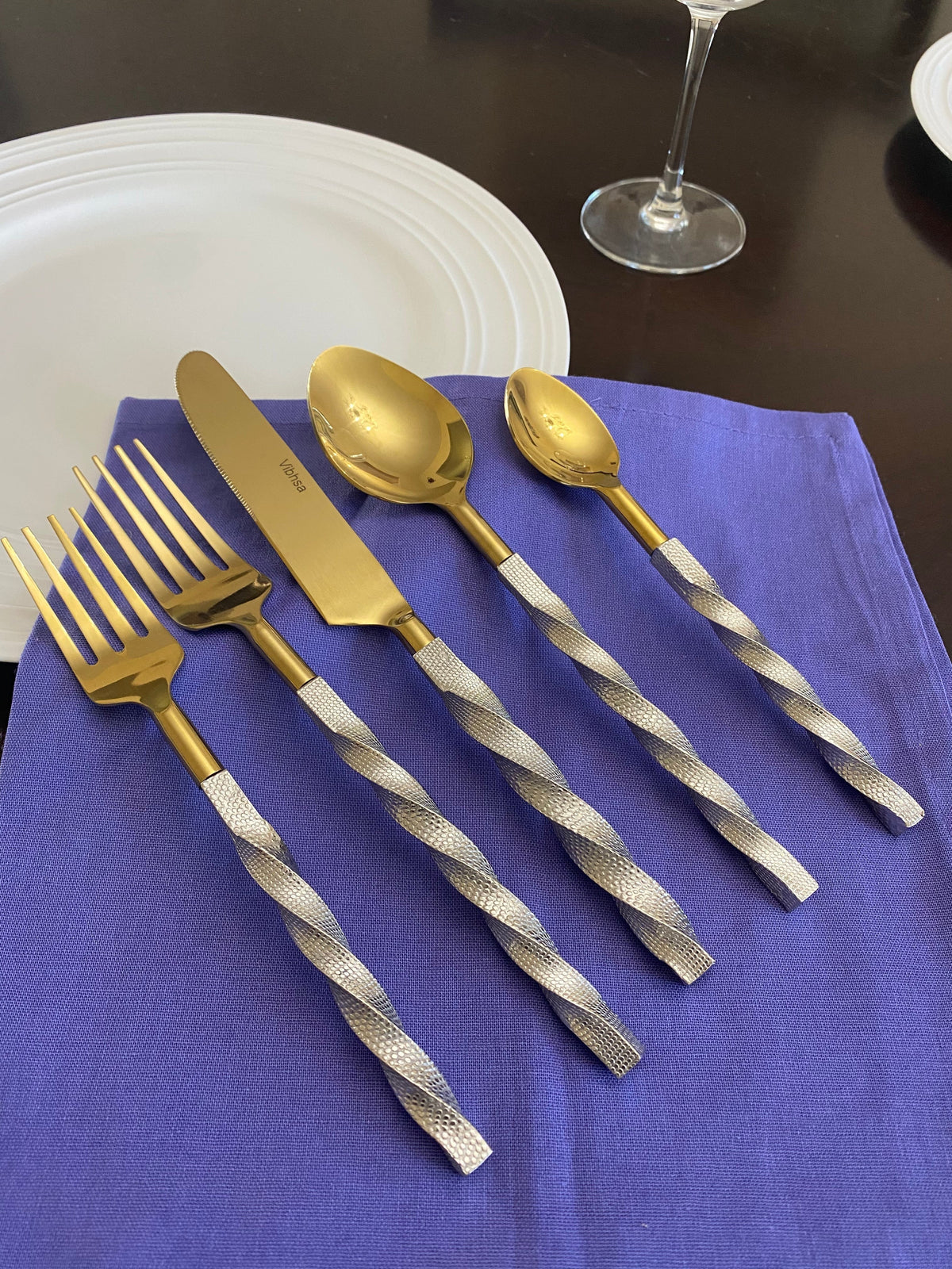 Vibhsa 20 pc gold stainless steel flatware set with twisted textured handles on purple napkin on Tampa Home & Garden Store