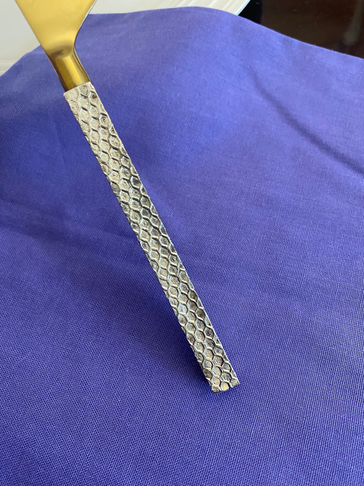 Vibhsa gold stainless steel flatware handle with hexagonal texture on purple fabric on Tampa Home & Garden Store