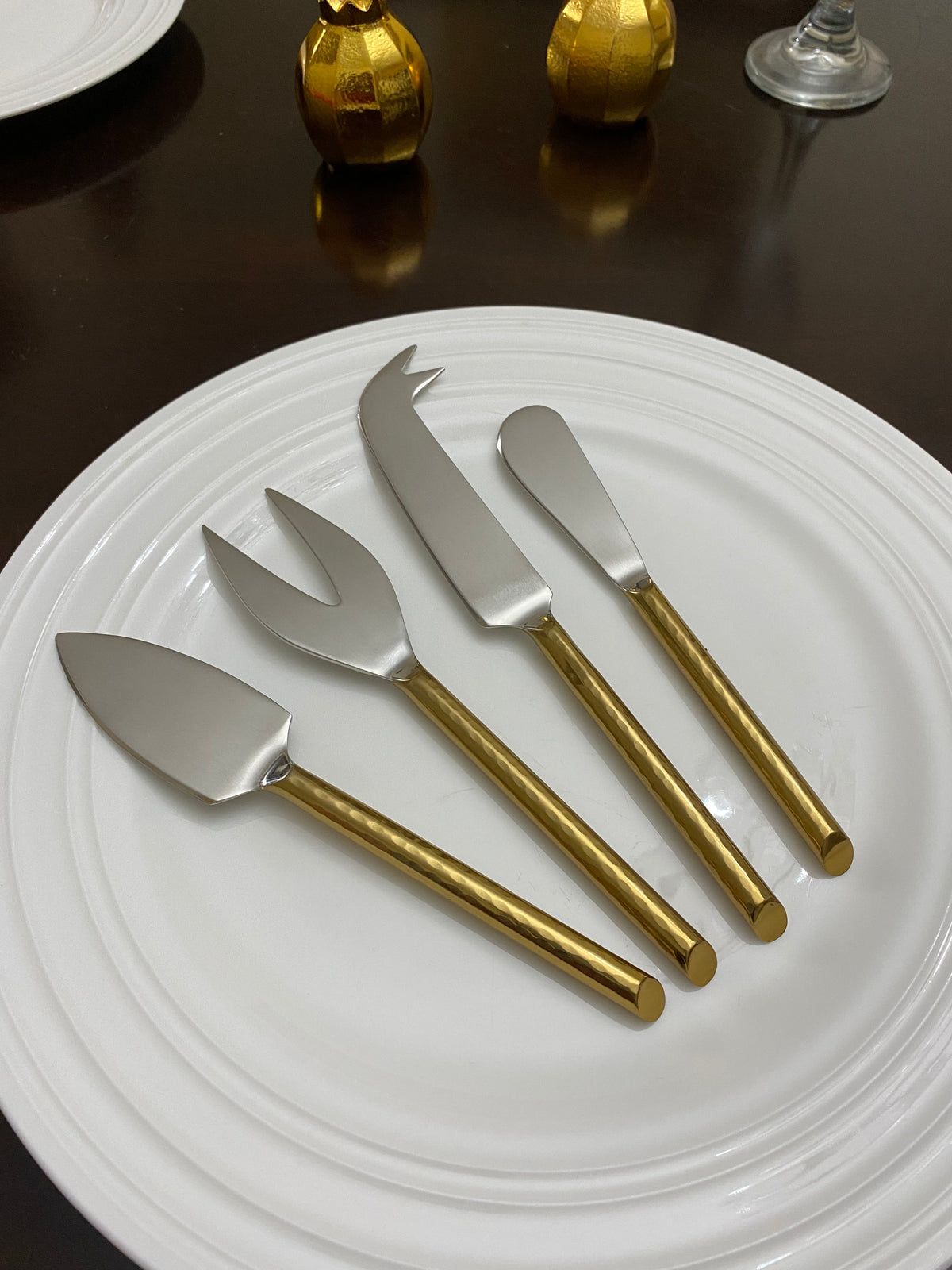 Vibhsa gold cheese knives set of 4 with hammered gold handles on white plate on Tampa Home & Garden Store