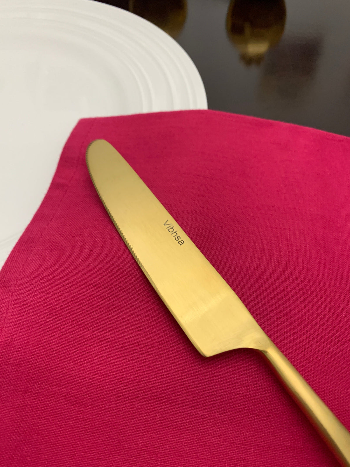 Flatware knife Vibhsa gold stainless Taj Look on magenta napkin beside white plate on Tampa Home & Garden Store