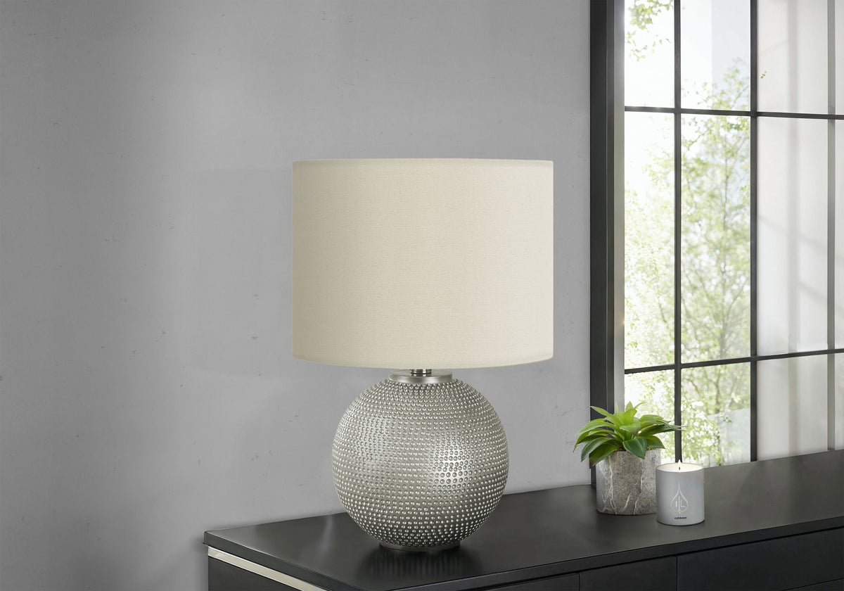 Table lamp with cream fabric shade and textured silver dotted globe base on a dark console on Tampa Home & Garden Store