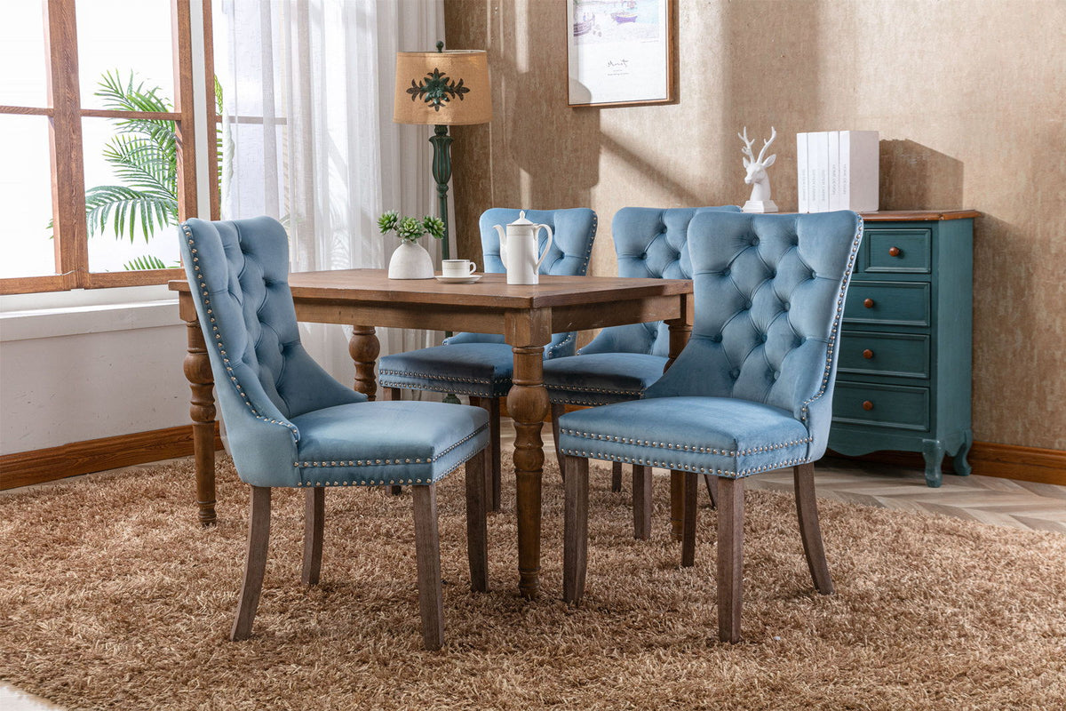 Tufted blue velvet dining chair set (4) with nailhead trim around edges around a wooden table on Tampa Home & Garden Store