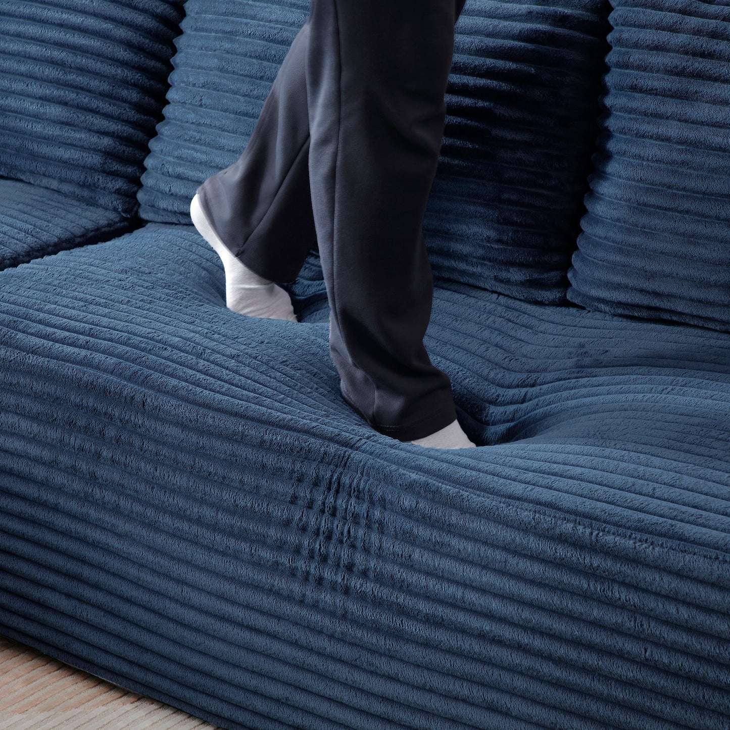 105'' Modular Sectional Sofa in deep blue fabric with chaise; person stepping on the sofa on Tampa Home & Garden Store
