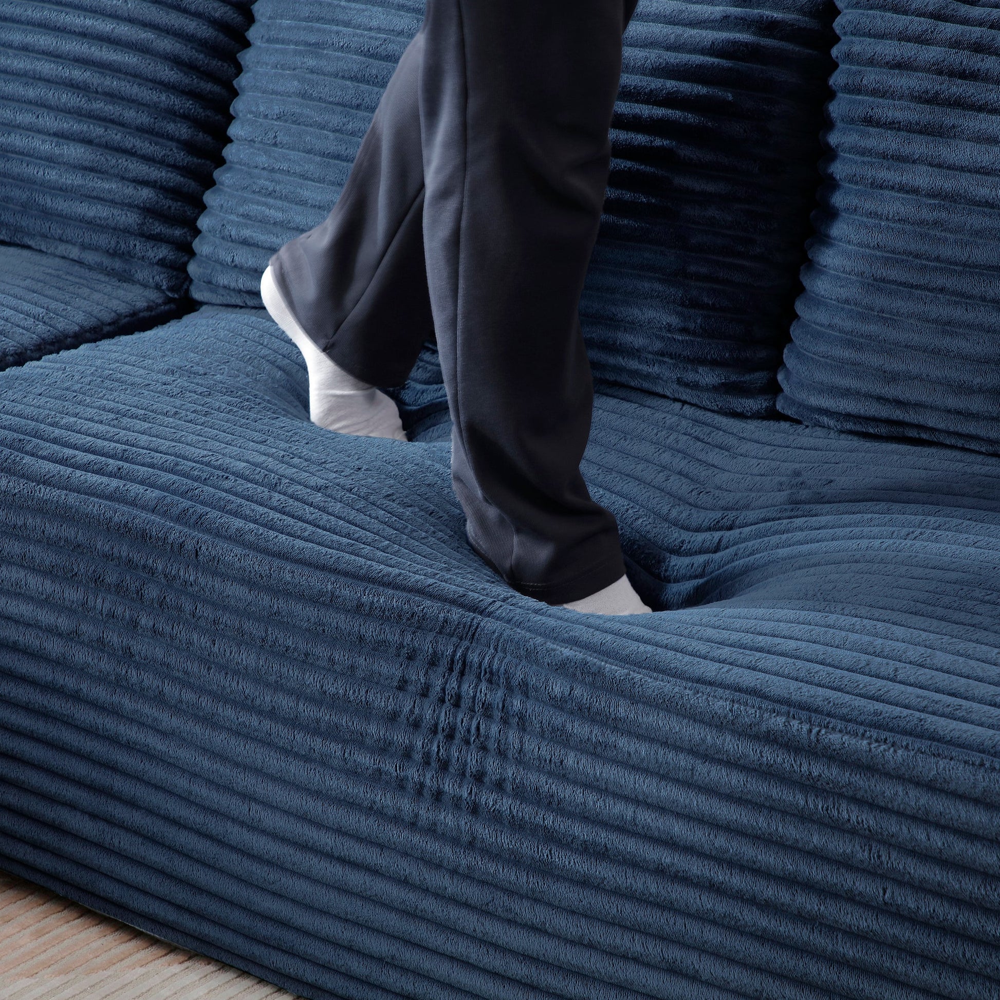 105'' Modular Sectional Sofa in deep blue fabric with chaise; person stepping on the sofa on Tampa Home & Garden Store