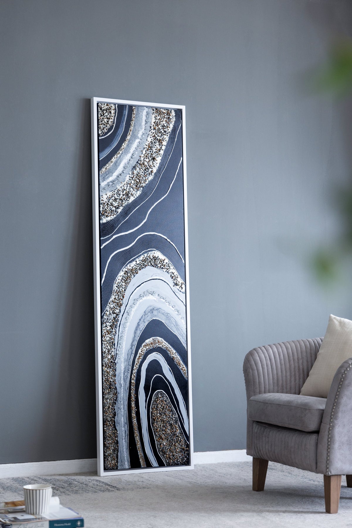 Elongated rectangle wall art with silver frame featuring blue-gray geode pattern, white contour lines, and gold pebble accents, leaning beside a gray wall on Tampa Home & Garden Store