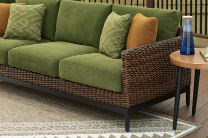 Horizon Hall sofa in green fabric with wicker base and brown pillow; cushions add color on Tampa Home & Garden Store