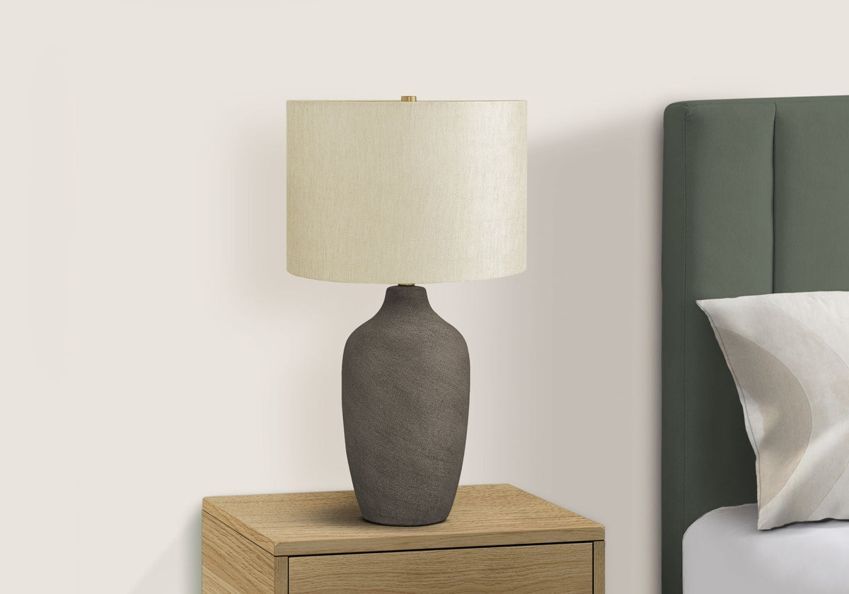 Table lamp in gray ceramic with fabric shade on nightstand beside green upholstered bed on Tampa Home & Garden Store