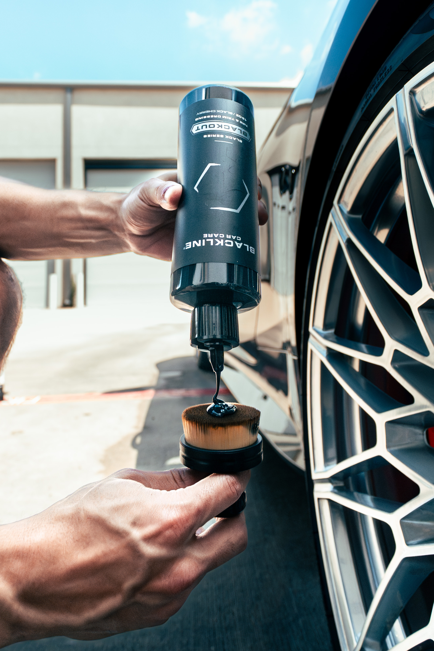 Blackline Blackout Trim & Tire Dressing bottle beside a car wheel, dark gray container on Tampa Home & Garden Store