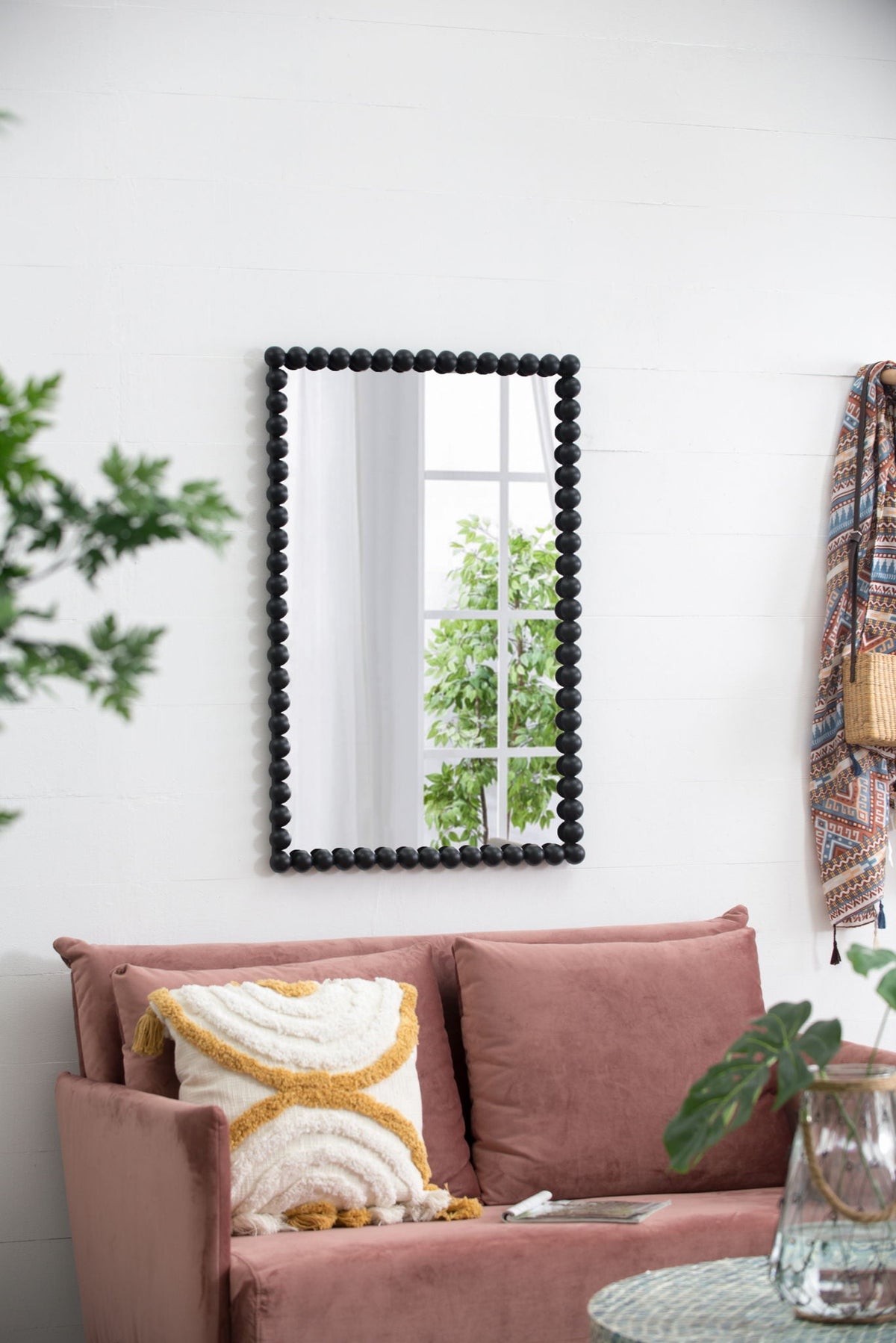 Rectangle wall mirror with a chunky black bead frame hanging on a white wall beside a pink sofa on Tampa Home & Garden Store