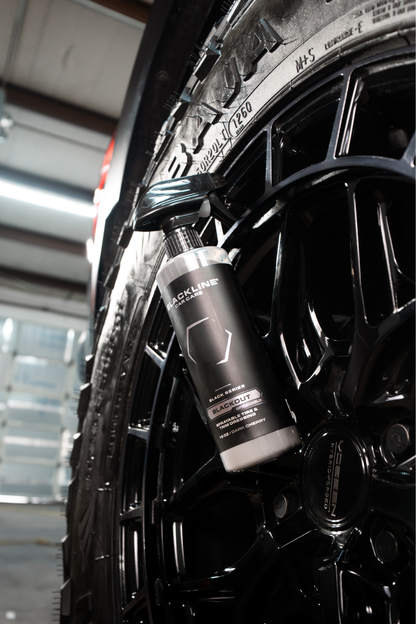BLACKLINE BLACKOUT TRIM & TIRE DRESSING spray bottle beside black alloy wheel on Tampa Home & Garden Store