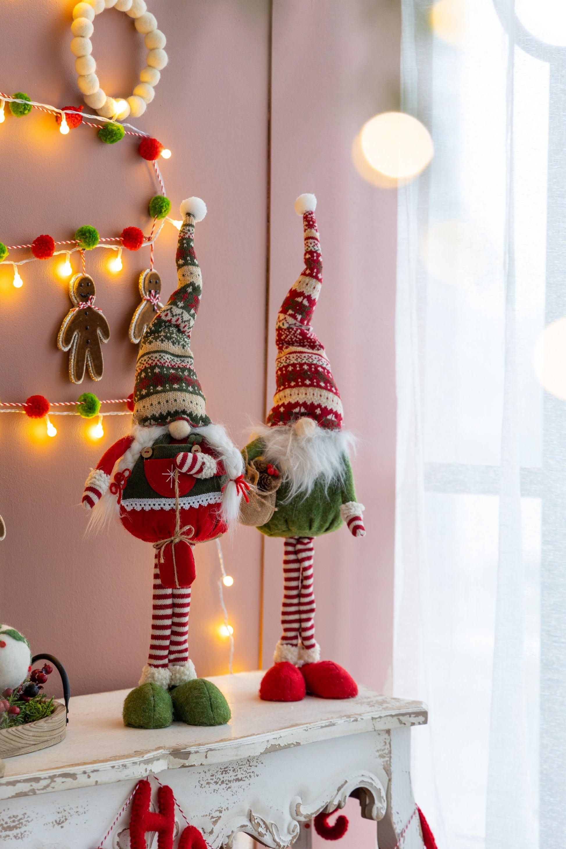 Set of 2 fabric standing Christmas gnomes with red and green striped hats beside warm lights on Tampa Home & Garden Store