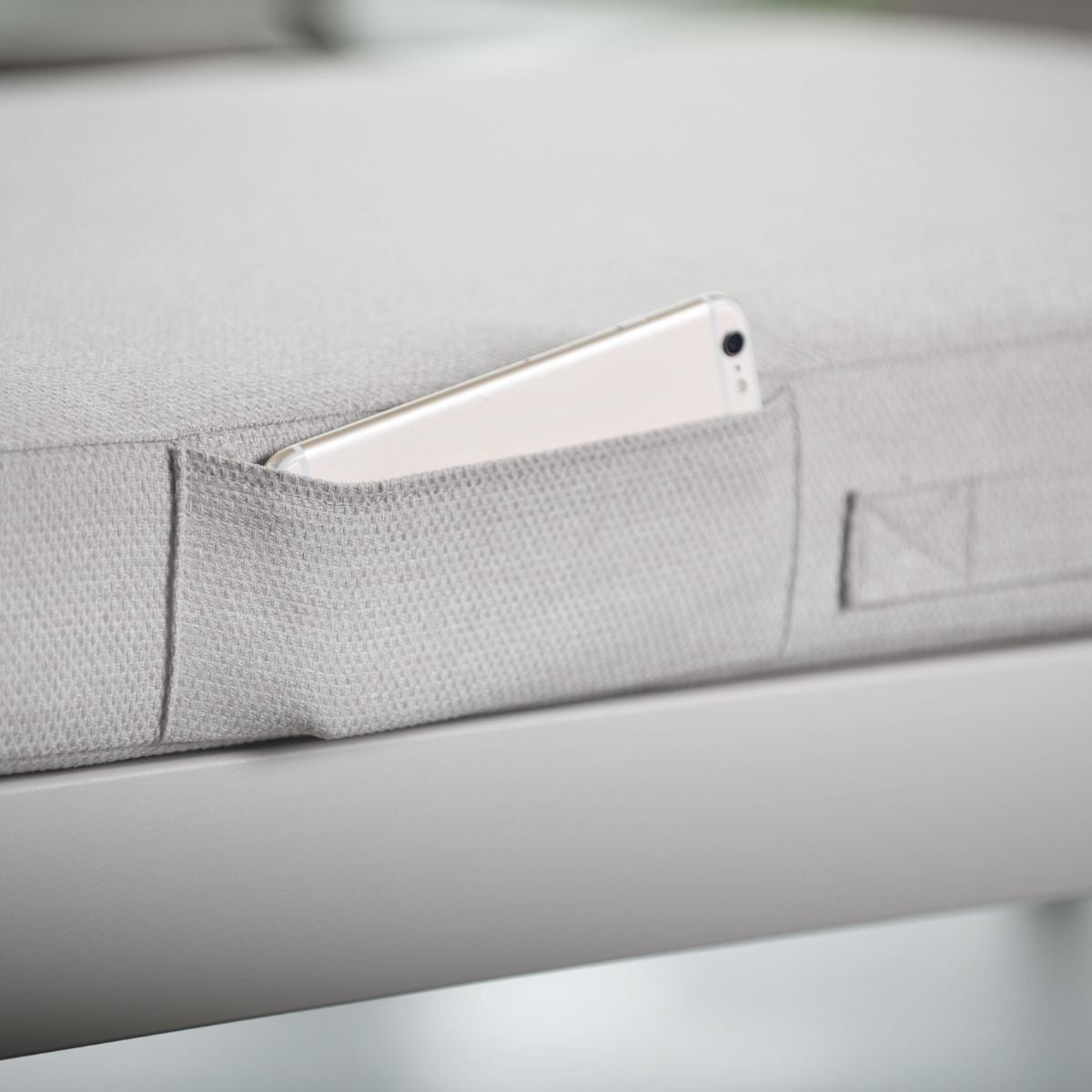 Portals Light 2-Seat Outdoor Sofa in gray fabric with side pocket holding a smartphone on Tampa Home & Garden Store