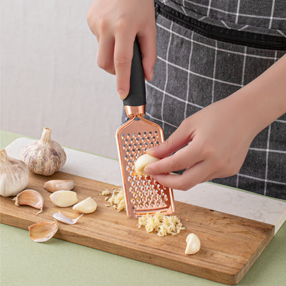Copper-plated kitchen grater with black handle grating garlic on a wooden board on Tampa Home & Garden Store