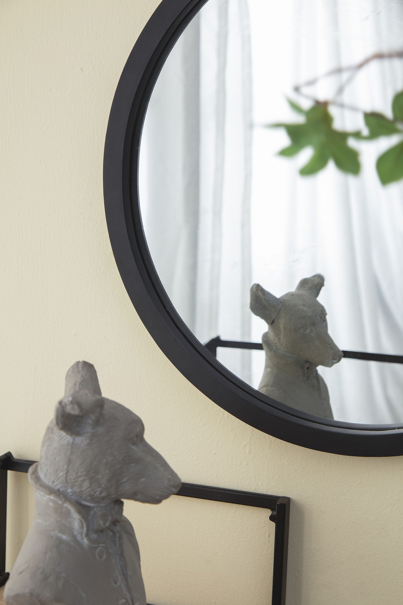 Circle Wall Mirror with a black round frame on pale yellow wall reflecting curtains and greenery on Tampa Home & Garden Store